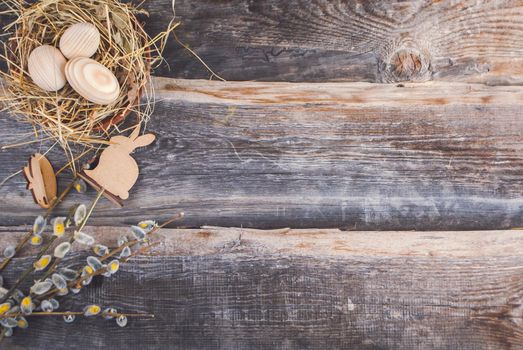 Easter decoration with wooden eggs in bascket and straw on wooden background