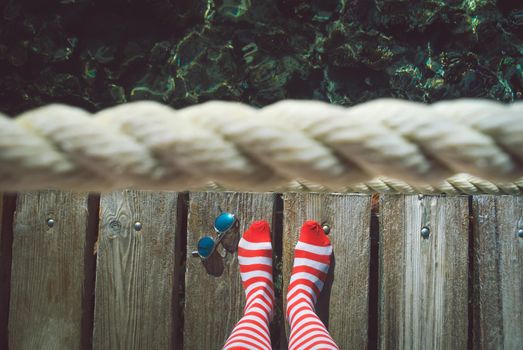 Concept of summer vacation with red striped socks and sunglesses on sea pier