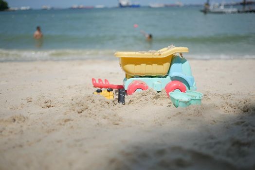 multi-colored plastic toys on a large sea sandy beach ,
