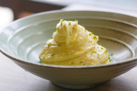 Mashed potatoes in bowl on wooden rustic table.
