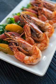 Grilled tiger prawns or shrimps with orange grapefruit and greens on a plate