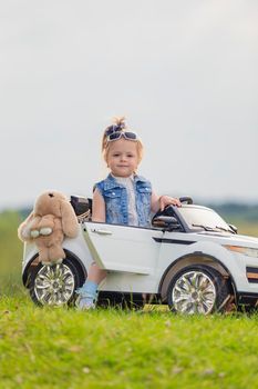 small child stands near his car on the lawn