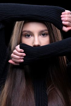 A beautiful brunette girl covered her face with her hands, leaving only her eyes.