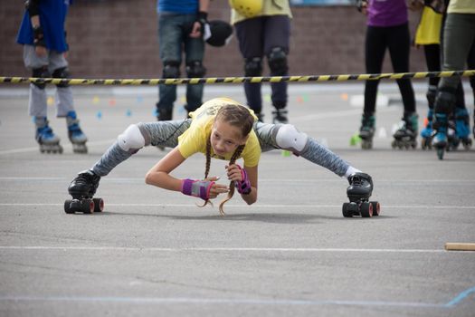 Belarus, Gomel, June 24, 2018. Central Park.Competition in roller sport.An athlete on roller skates rides under the barbell.Incredible stretching of a girl on roller skates. Unusual way to ride on rollers