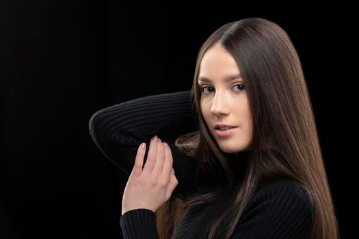 Beautiful young girl with long straight hair on a dark background.