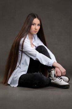 Beautiful brunette girl with very long hair on a gray background.