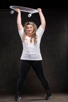 A beautiful fat woman wants to throw a skateboard on the floor. The girl is a plus size model.