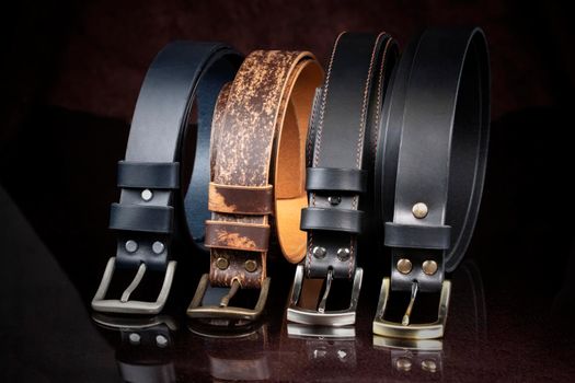 Group of leather belts on a dark background.