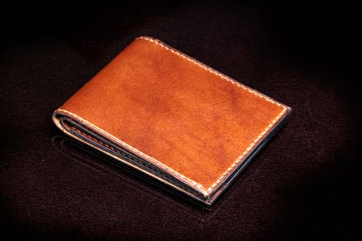 Brown leather wallet on a dark background.