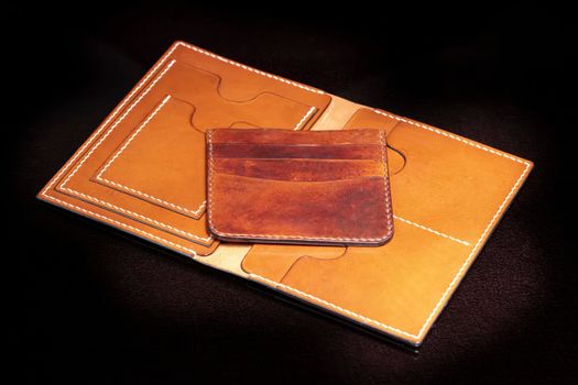 Open leather brown purse with pockets on a dark background.