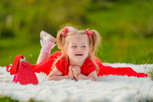little girl in a red dress lies on a white blanket