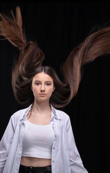 Beautiful brunette with long flying hair on a dark background.