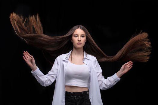 Beautiful brunette with long flying hair on a dark background.