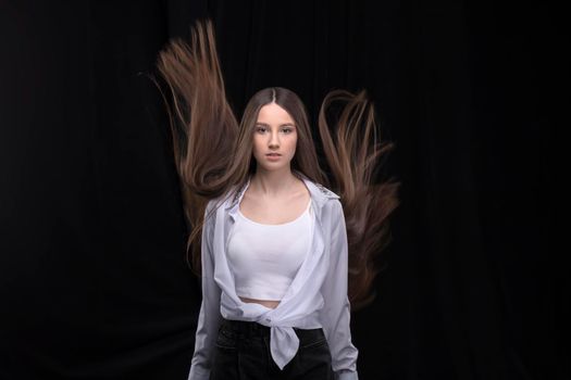 Beautiful brunette with long flying hair on a dark background.