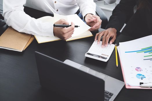 Two young business executives are discussing and using calculator calculate to increase profits and the strength of their business.