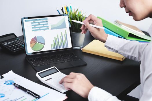 The young businessman using tablet computer and calculators to check financial statements at home instead of working in the office.