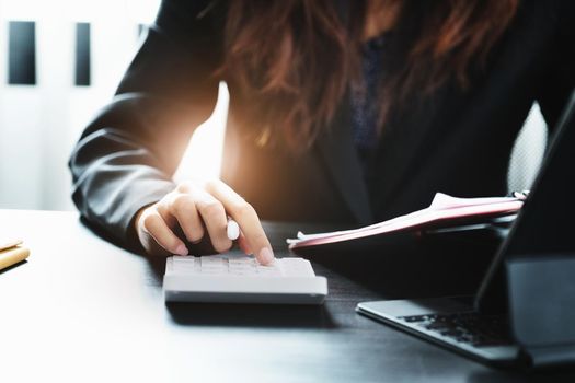 Business woman using calculator to review balance sheet annual using document and laptop computer to calculating budget. audit and Check integrity before investment concept.