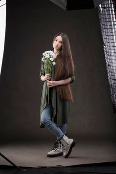 Beautiful brunette girl with very long hair under studio equipment in a photo studio. Woman fashion model posing at the camera.