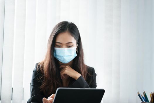 social distancing, Business woman using tablet to review balance sheet annual and calculating budget in office. audit and Check integrity before investment concept