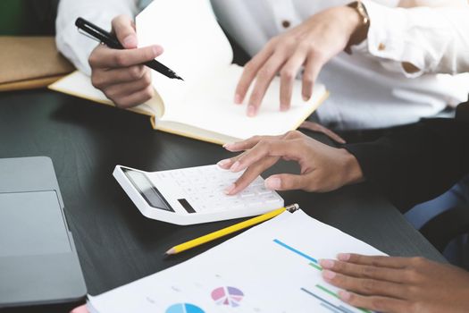 Two young business executives are discussing and using calculator calculate to increase profits and the strength of their business.