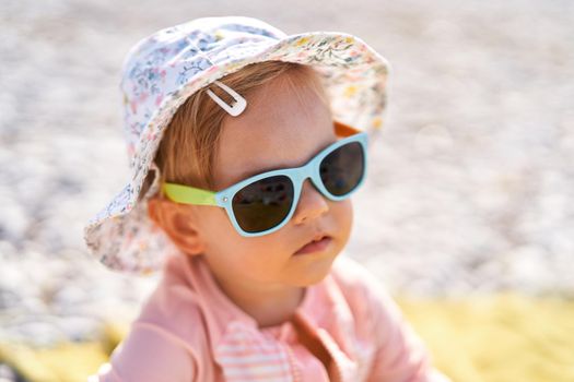 Little girl in sunglasses on the beach. High quality photo