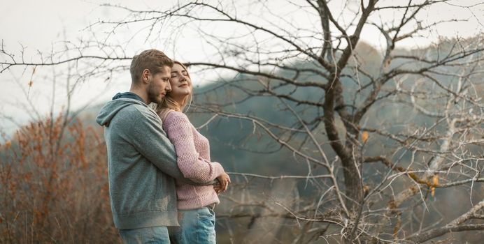 Loving Couple Enjoy The Beauty Of Nature, Caucasian Guy Embraced His Smiling Girl In A Pink Jumper, Two People Casual Clothing Are Resting Against The Backdrop Of Autumn Nature