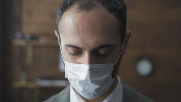 Serious Businessman In Medical Protective Mask Looking Down, Sad Middle Eastern Man Standing Alone In Board Room, Man Forced To Remain On Self-Isolation Due To Coronavirus Outbreak, Quarantine Concept