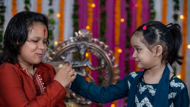 Indian families celebrating Raksha Bandhan festival a festival to celebrate the bond between brother and sister. Rakhi celebration in India. Feeding sweets, applying tikka.