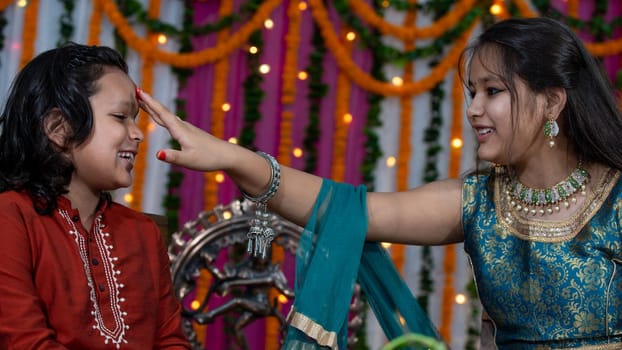 Indian families celebrating Raksha Bandhan festival a festival to celebrate the bond between brother and sister. Rakhi celebration in India. Feeding sweets, applying tikka.