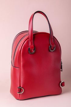 Fashionable female backpack on a pink background. Leather red backpack with an iron zipper. Back view