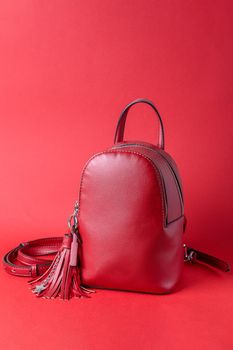 Fashionable female backpack on a red background. Leather red backpack with an iron zipper. Close-up.