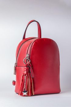 Fashionable female backpack on a white background. Leather red backpack with an iron zipper. Close-up.