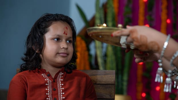 Indian families celebrating Raksha Bandhan festival a festival to celebrate the bond between brother and sister. Rakhi celebration in India. Feeding sweets, applying tikka.