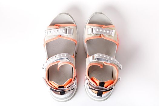 Women's, fashionable, sports sandals with orange accents on a white background. New youth shoes for girls. View from above.