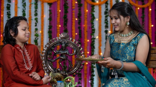 Indian families celebrating Raksha Bandhan festival a festival to celebrate the bond between brother and sister. Rakhi celebration in India. Feeding sweets, applying tikka.