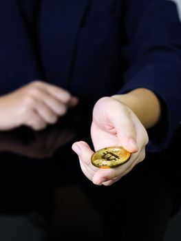 Close up of businesswoman holding some pieces of golden Bitcoin token , Bitcoin is one of the popular cryptocurrency