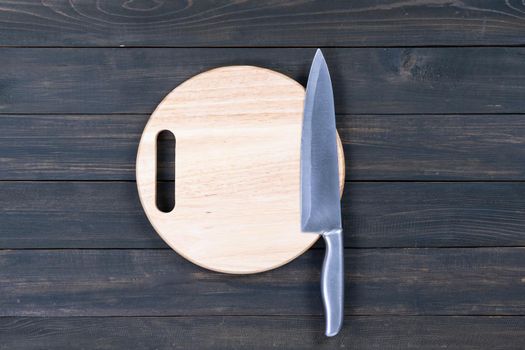 Close up kitchen knife and wooden round empty cutting board on a wooden table