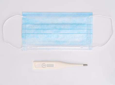 Medical respiratory surgical face mask filter with digital clinical thermometer ,Close-up of surgical medical mask on white background