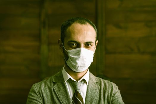 Confidence Businessman Wearing A Protective Mask Is Forced To Be Isolated Due To Quarantine Over Coronavirus Epidemic, Middle Eastern Man Stands Against Wooden Wall Looking At Camera, Toned Image