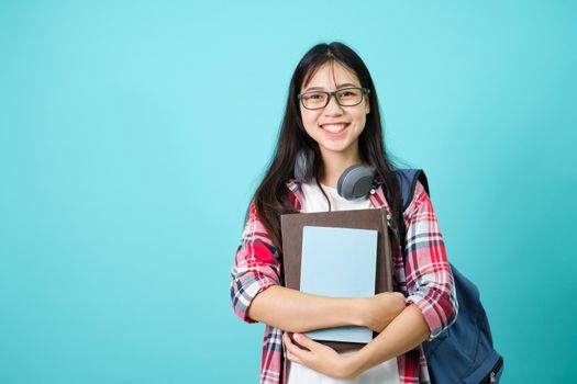 Happy Student. Cheerful Asian Girl Smiling To Camera Standing With Backpack In Studio Over Blue Background. Back to school concept.