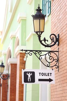 toilet sign hanging on brick wall and vintage lamp