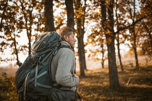 Bearded Traveler With Large Backpack Walking Along A Forest Path Among The Trees Outdoors In Sunny Autumn Day, Side View Of Caucasian Guy Breathes Fresh Air Into His Lungs