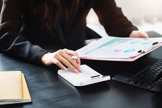 Business woman using calculator to review balance sheet annual using document and laptop computer to calculating budget. audit and Check integrity before investment concept.