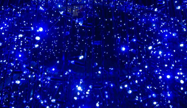 Beautiful abstract image of festive blue electric lights at night. Holiday decoration made of small electric lights.