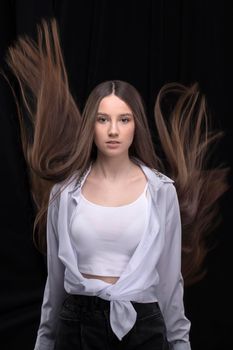 Beautiful brunette with long flying hair on a dark background.