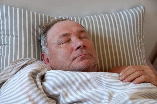 sick man lying in bed with closed eyes close-up