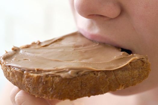 girl biting a sandwich with chocolate paste close-up