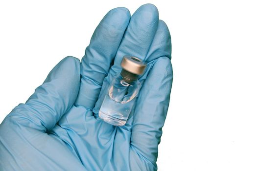 A hand in a blue medical glove close-up holding a vaccine against a light background. The concept of the fight against Covid19..