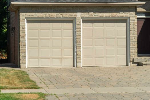 Two garage doors with a paved stone tile entrance near the entrance