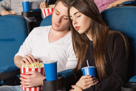 Could have stayed home. Shot of a beautiful bored couple sleeping during a movie at the local cinema